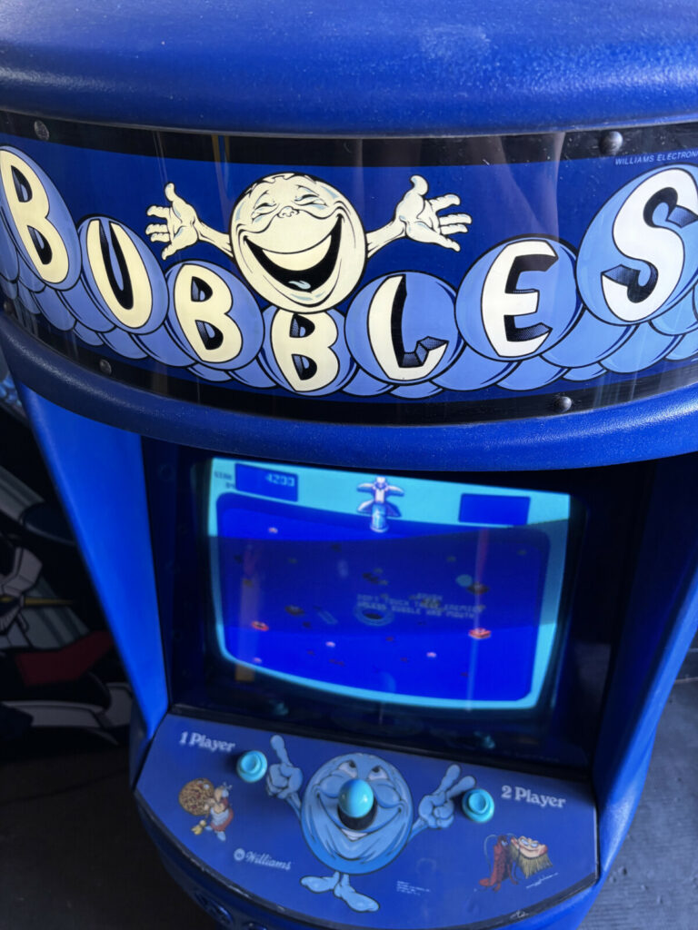 Dettaglio frontale del cabinato arcade Bubbles (Williams, 1982) che mostra il tendalino marquee originale sagomato e il vetro del monitor.