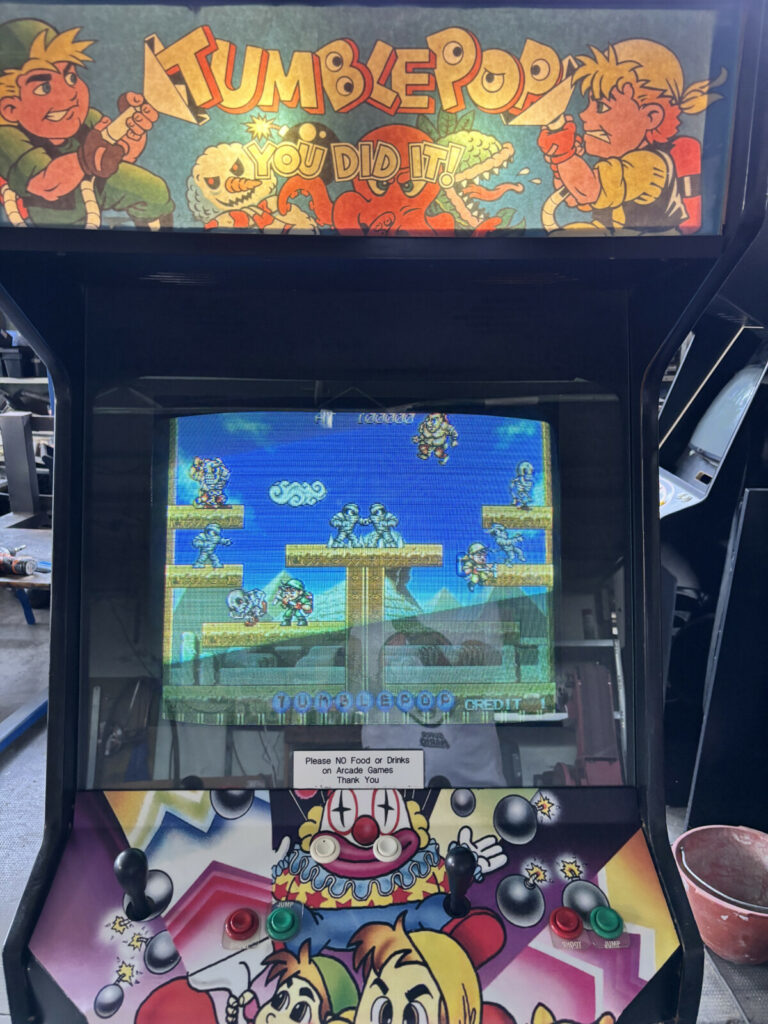 Primo piano della plancia comandi a due giocatori e del monitor CRT che mostra una fase di gioco del videogioco arcade Tumblepop della Data East