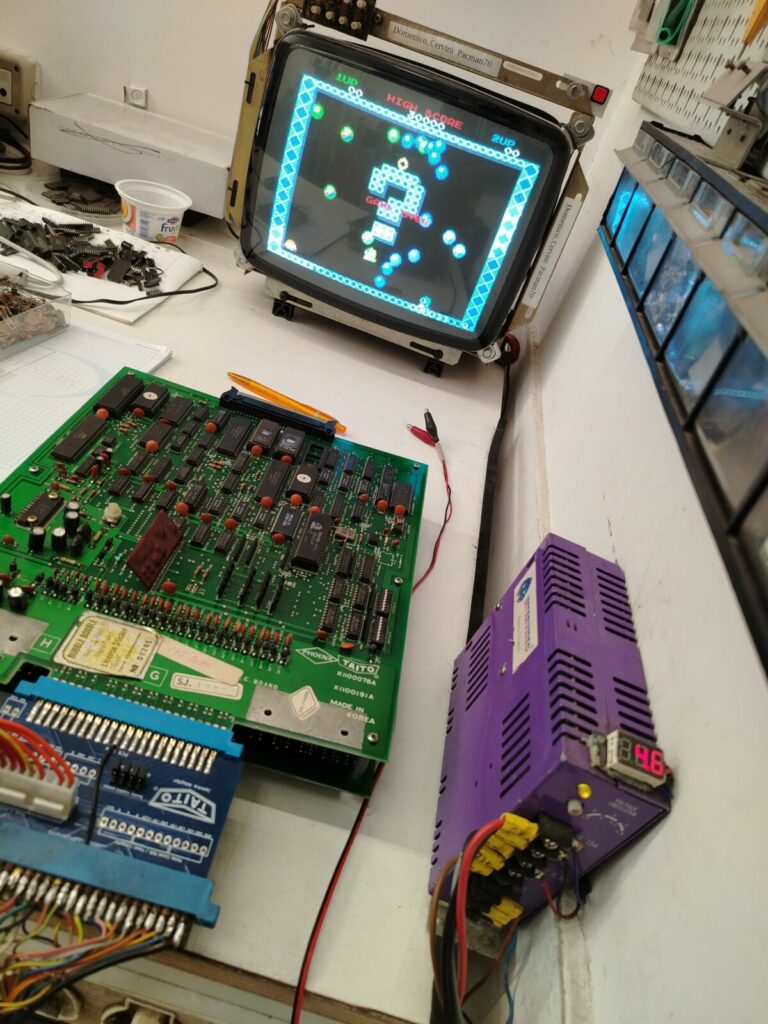 Scheda logica di Bubble Bobble perfettamente restaurata e in funzione su monitor CRT originale, alimentata con tensione ottimizzata a 4,6 volt per garantirne la preservazione storica