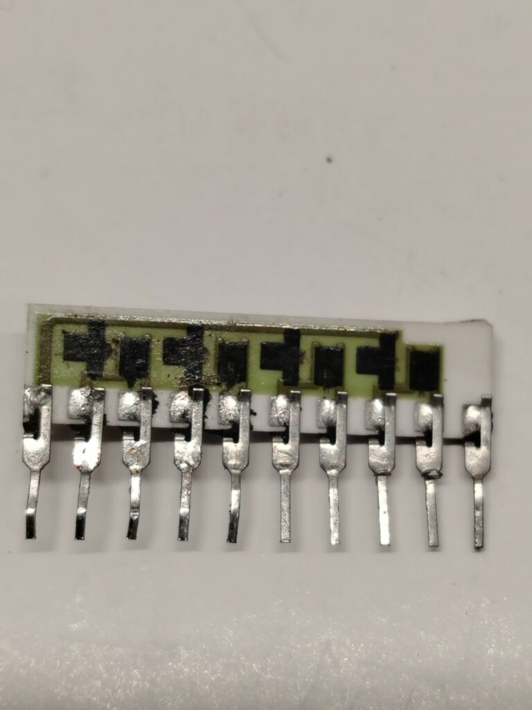 Fotografia macro di un componente elettronico custom TRJ-001 estratto da una scheda arcade. L'involucro di plastica esterna è stato rimosso chimicamente nel laboratorio Arcade Story per esporre e riparare i contatti interni bruciati, salvando la PCB originale