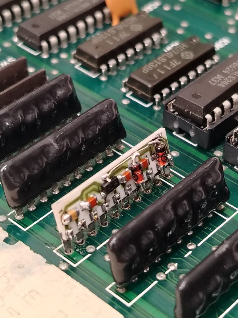 Fotografia macro di un componente elettronico custom TRJ-001 riparato e saldato sulla sua scheda di Double Dragon originale.