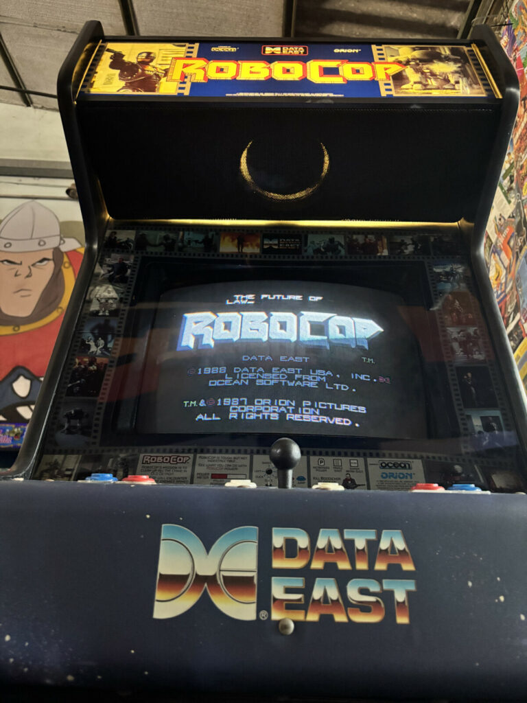 Particolare e suggestiva vista dal basso verso l'alto del cabinato Data East di RoboCop, che ne esalta la stazza e mostra i dettagli della gettoniera arcade.