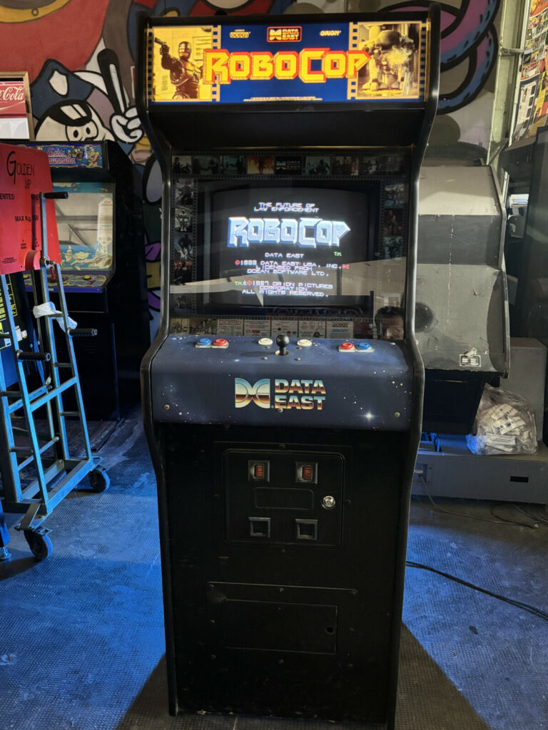 Vista frontale completa dell'imponente cabinato arcade di RoboCop, dalla gettoniera classica in basso fino al favoloso marquee illuminato in alto.